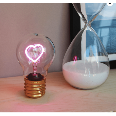 Lampadina LED Cuore accesa con luce rosa, in ambiente domestico su mobile accanto a clessidra, Lamp-Adina's NelQuieOra