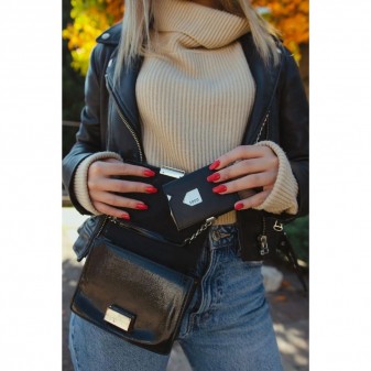 Primo piano di una donna con giacca in pelle e jeans che tiene un portafoglio compatto Exentri nero